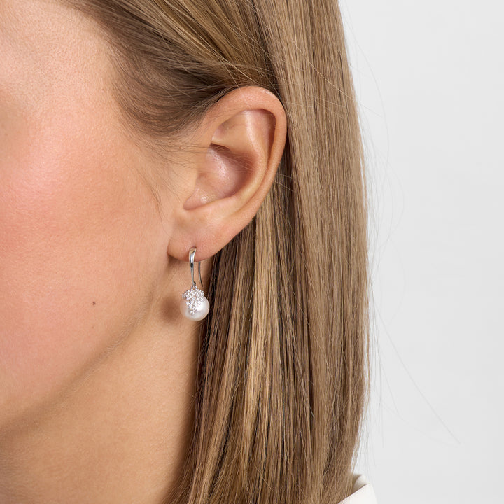 Zilveren oorbel met witte parel en steen, afgebeeld op het oor, model 2113025, voorkant