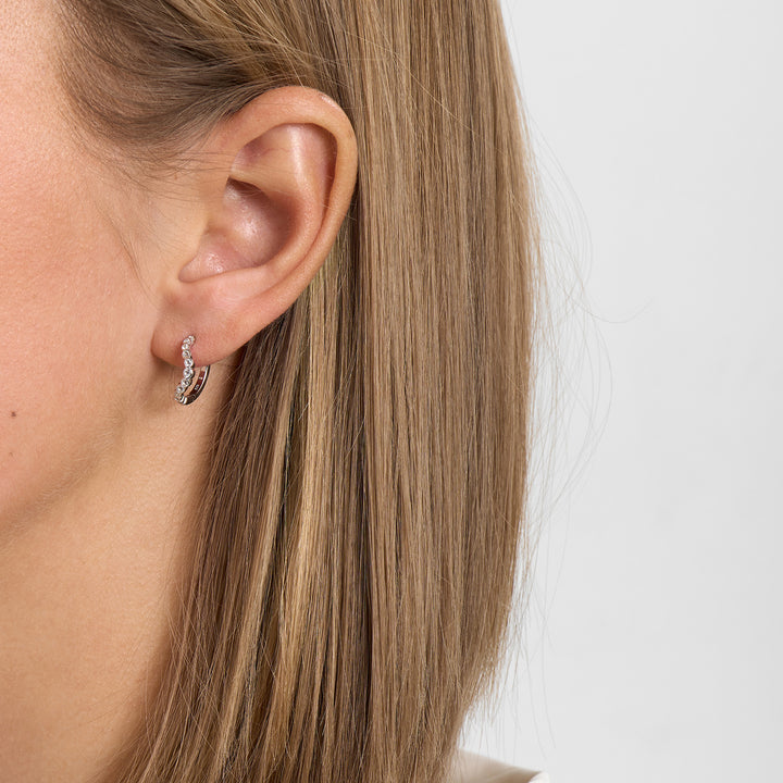 Oorbel in zilver met heldere stenen, modelafbeelding vanaf de zijkant in het oor weergegeven