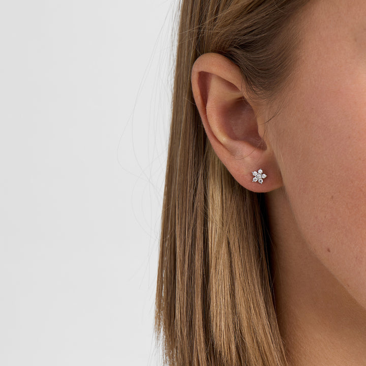 Oorbellen in zilver met bloemmotieven en heldere stenen, afgebeeld op het oor op de profielfoto