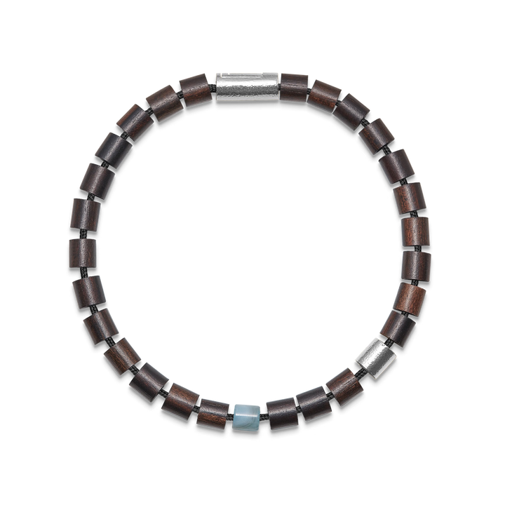 Armbånd med mørkebrune træperler, sølvfarvet detalje og en lyseblå sten på sort baggrund.
