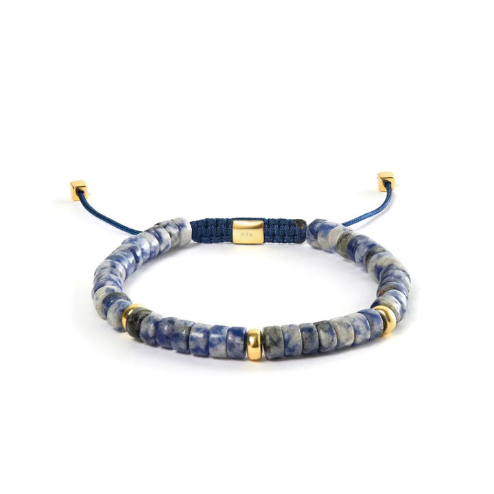 Alexander Lynggaard Armband Blue Spot Jasper Heishi Gevlochten 6 mm met blauwe en gouden details op een witte achtergrond. ModelB00222-1.