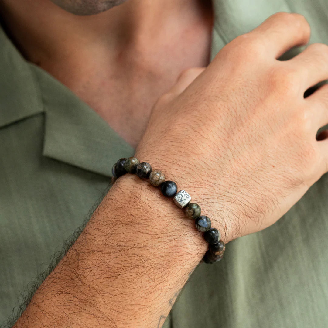 Alexander Lynggaard Armband Glaucofaan 8 mm afgebeeld op de hand van een man, kralen in blauwbruine tinten. ModelC01180-001.