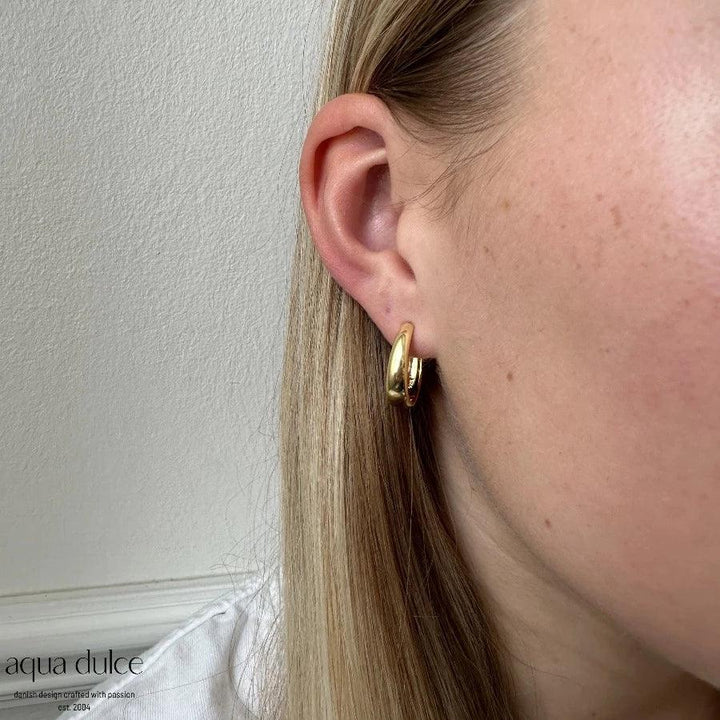 Aqua Dulce Big Emma Hoop verzilverde oorbel afgebeeld op het oor, glanzende gouden afwerking. Model 5535-5535-2