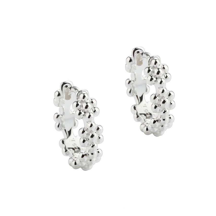 Aqua Dulce Lots of Flowers Hoop Silver 13mm 5705–1 toont een paar zilveren oorringen met bloemendetails. Model 5705–1.