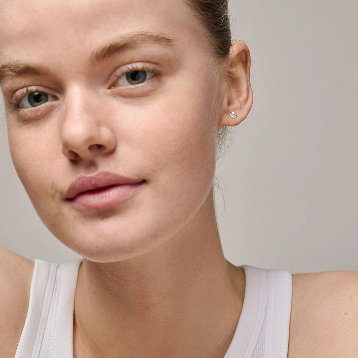 Enamel Organische klaver kleine klavertje vier oorbellen in zilver te zien op het oor van het model, discreet ontwerp Model e412sm