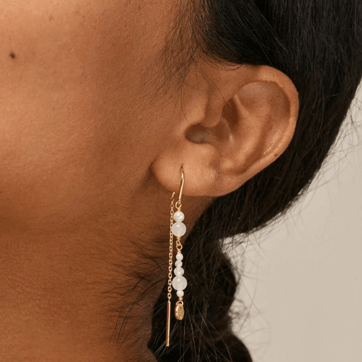 Enamel Sofia Earings White en Pearls afgebeeld gedragen in het oor, lange vergulde oorbellen met witte parels. Model e282g-wit-2