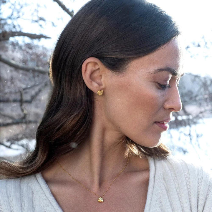 Flora Danica Sparrenklaver ketting 18kt goud getoond gedragen door een vrouw in de natuur met model flc-ne-18k-g-2.