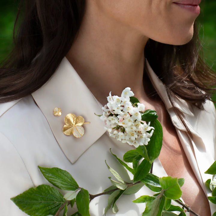 Flora Danica Fir Clover Pin Pavé Gilded wordt gedragen op een licht overhemd, gouden detail met stenen. Model 907-flc-pi-g-pave-2