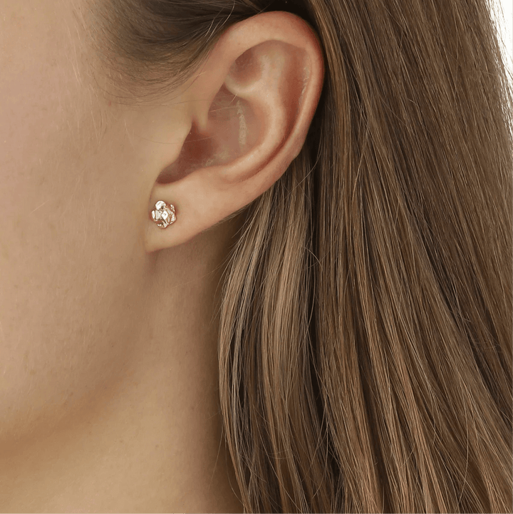 Flora Danica Vergeet de kleine oorknopjes. 18kt goud afgebeeld op het oor, gedetailleerd bloemmotief. Model fmn-stpc-18k-g-2