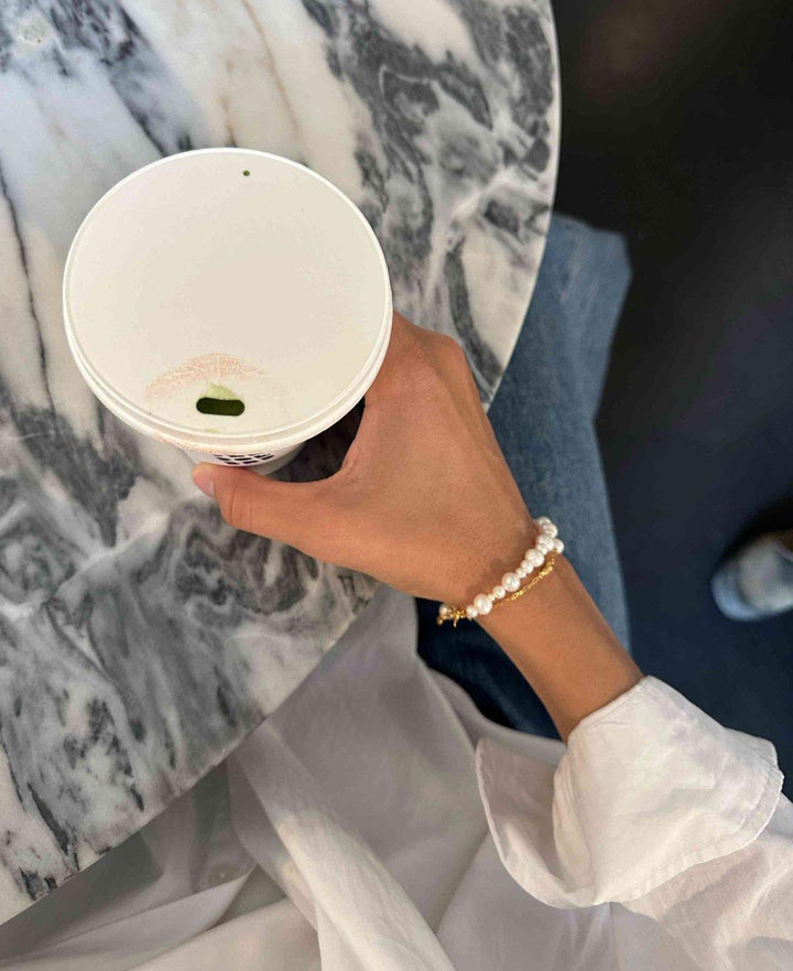 Hultquist Copenhagen Josephine armband met witte parels en gouden details gedragen bij de hand, model S08559G-2.