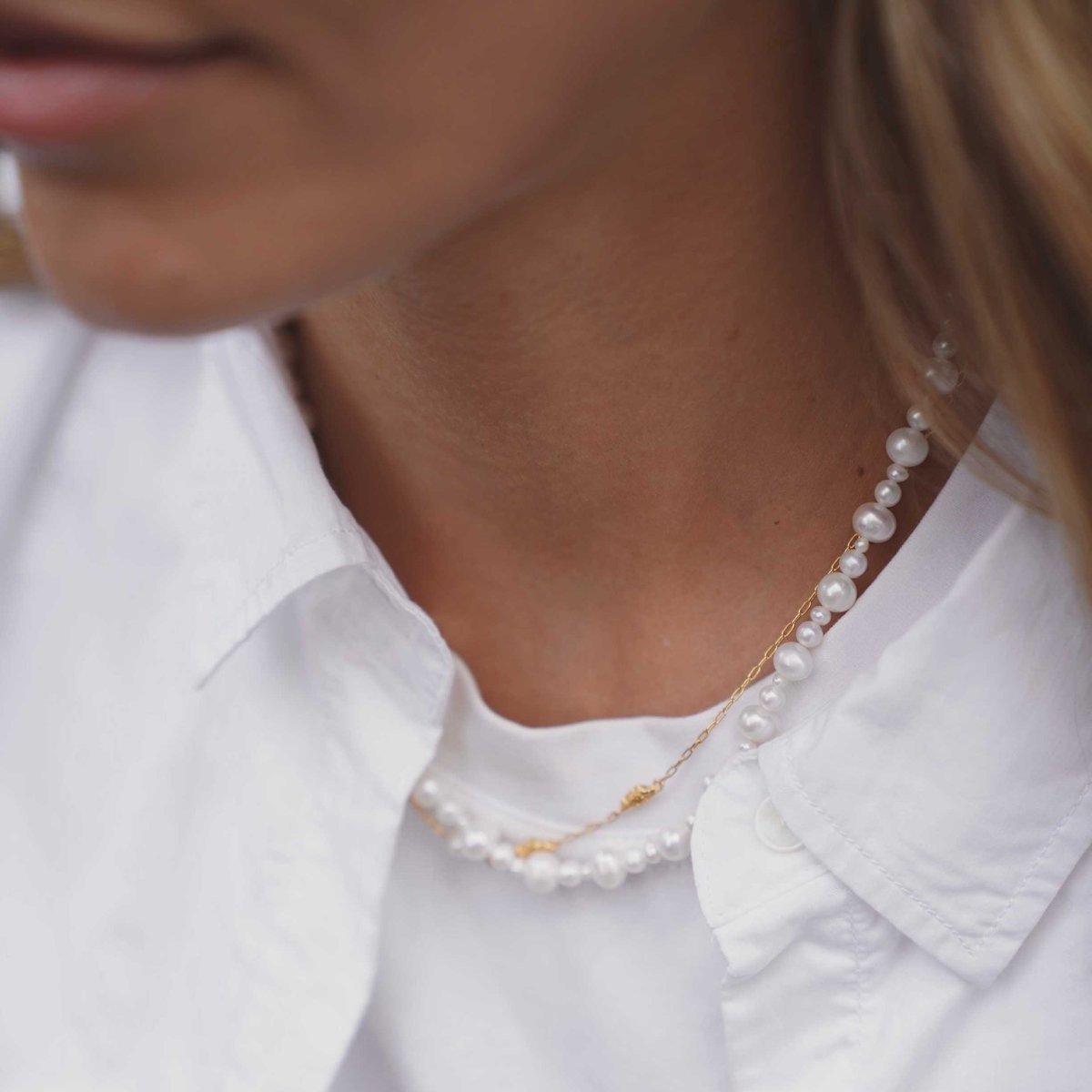 Hultquist Copenhagen Josephine Perle Halsketting met witte zoetwaterparels en gouden ketting gedragen over een wit overhemd. ModelS08558G-1