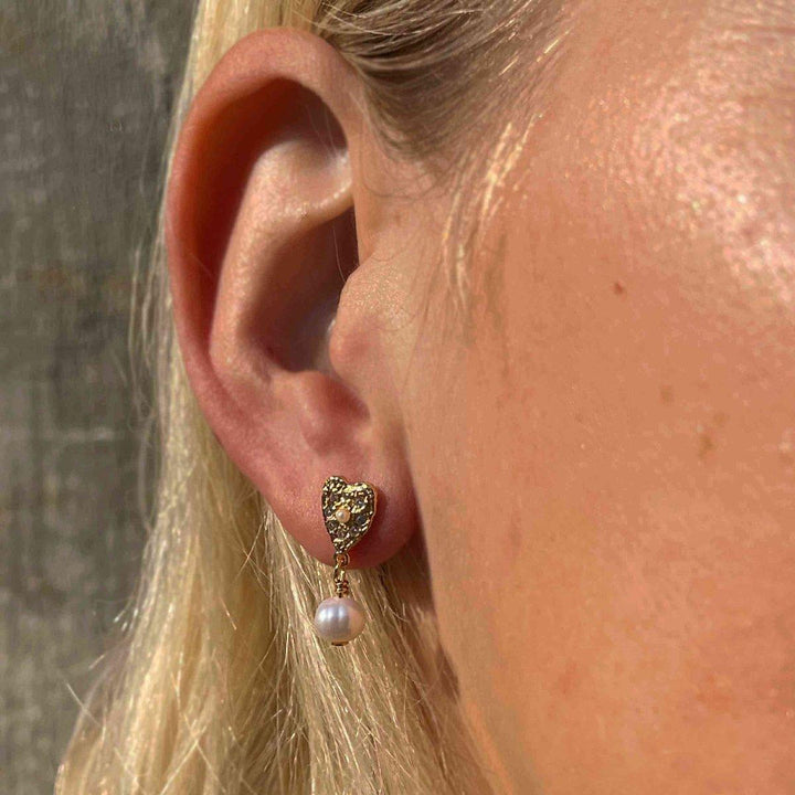 Hultquist Copenhagen Lucia Pearl Heart-oorbellen in goud met witte parel gedragen op het oor, model S08548G-2