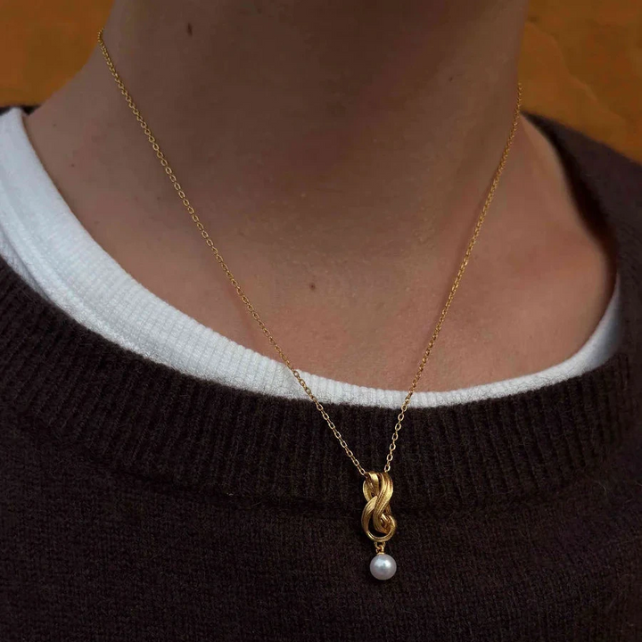 Hultquist Tiril Ketting Verguld gezien op model, elegante gouden ketting met gevlochten hanger en parel. ModelS08646G-2.