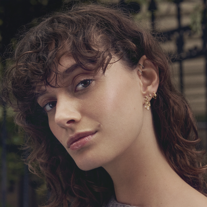 Maanesten Forte vergulde creolen in een elegant bloemmotief worden gedragen door model, Model 10021a-2.