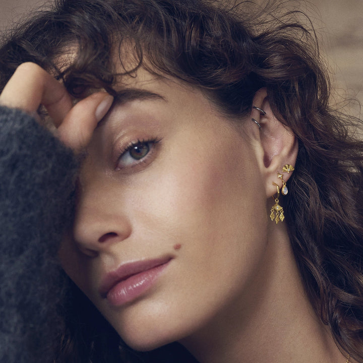 maanesten poco vergulde oorbellen afgebeeld op model, gedetailleerde gouden look en elegant design. Model 10043a