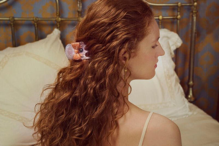 maanesten-ruku-hair-claw-dawn in paars en roze acryl is te zien in lang, golvend haar bij een vrouw. Model3972-2