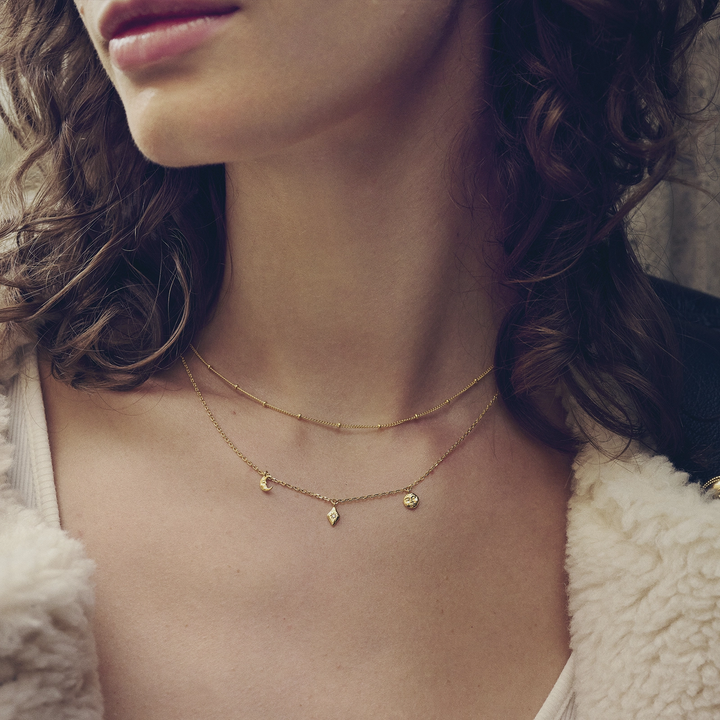 Maanestens Lea vergulde ketting afgebeeld op model, elegante ketting met kleine hangers in goud, Model 2806a-2