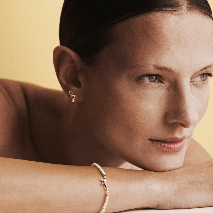 Mads Z Miss Butterfly Bow Pearl armband goud en diamanten, gedragen door vrouw tegen lichte achtergrond. Model1553030-2