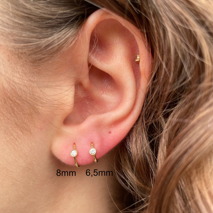 Maria Tash 6,5 mm Scalloped Diamond Clicker 18kt goud verschijnt in het oor, elegant en discreet. Model xrsc65d-2.