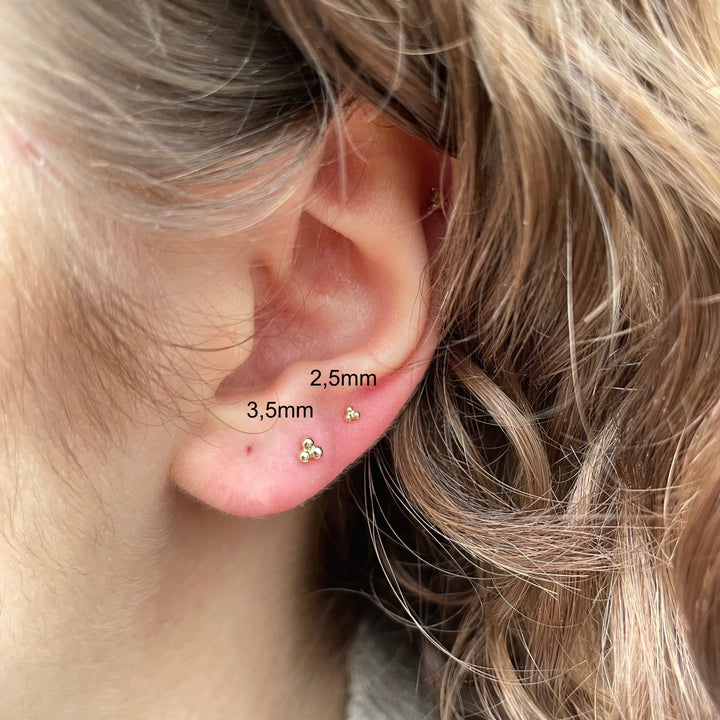 Maria Tash Ball Trinity Threaded Stud 2,5 mm in goud, elegant detail in het oor op persoon, Model xbtr-yg-w25-001-2