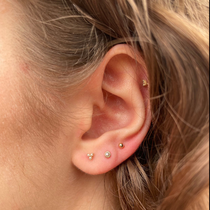 Maria Tash Natural Pearl Threaded Stud Earring 14kt wordt weergegeven in een oor, discrete zoetwaterparel op goud. Model xpe-yg-w2-001-2.