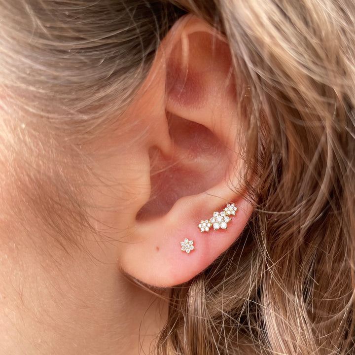 Maria Tash Three Flower Garland Diamond Stud Earring 18k is te zien in het oor, met fonkelende diamanten in een bloemmotief. Modelxc3fld-002-2.