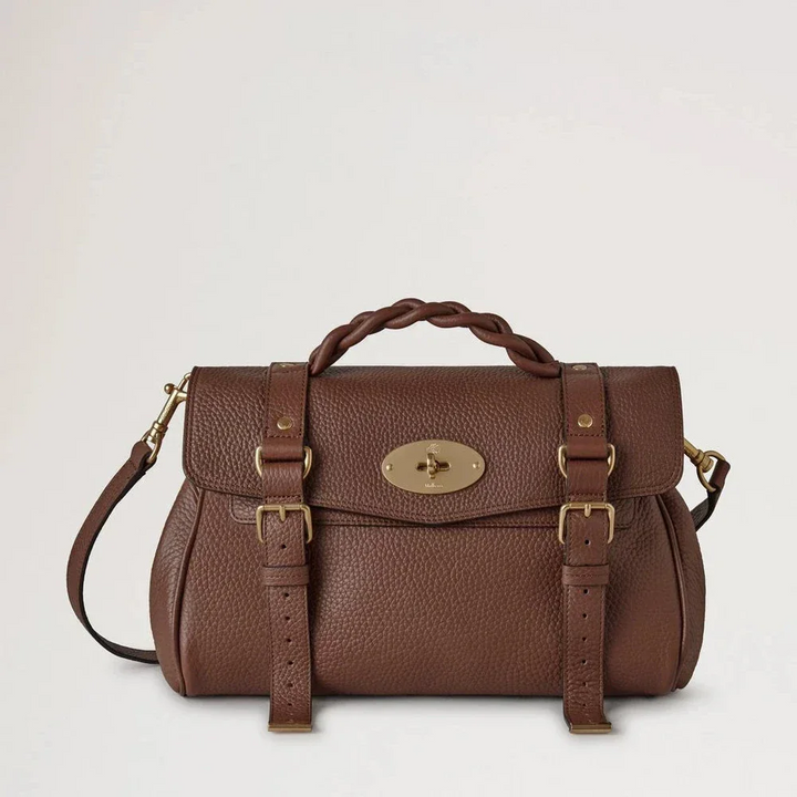 Mulberry Alexa Heavy Grain Bright Oak toont een bruinleren tas met gevlochten handvat en gouden details. ModelHH6746/736G222.
