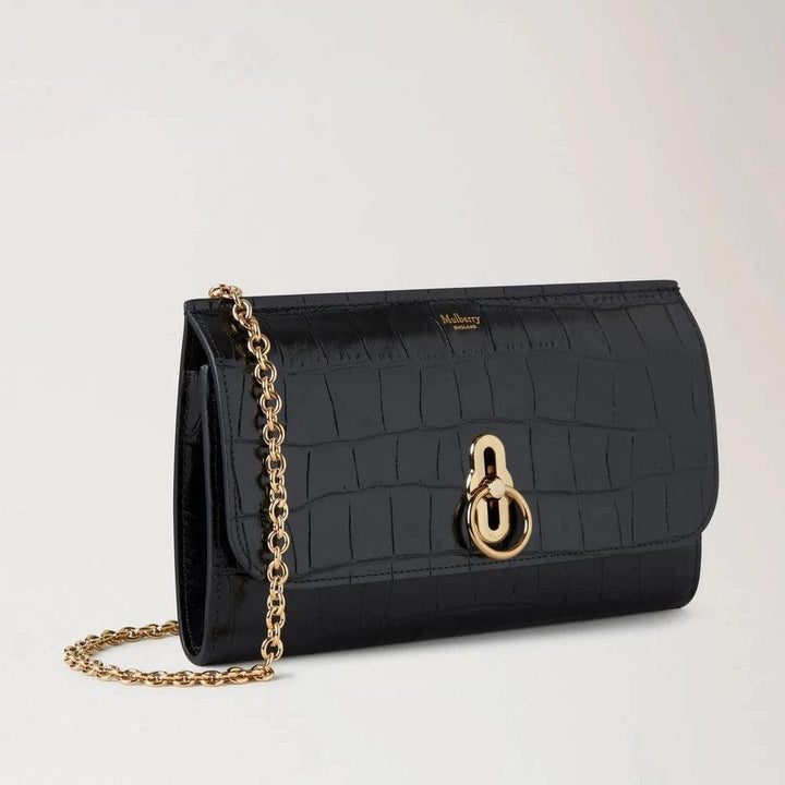 Mulberry Amberley Clutch Black Shiny Small Croc toont een zwarte clutch van glanzend leer met krokodillenreliëf, gouden ketting en sluiting. ModelRL8191641A100.