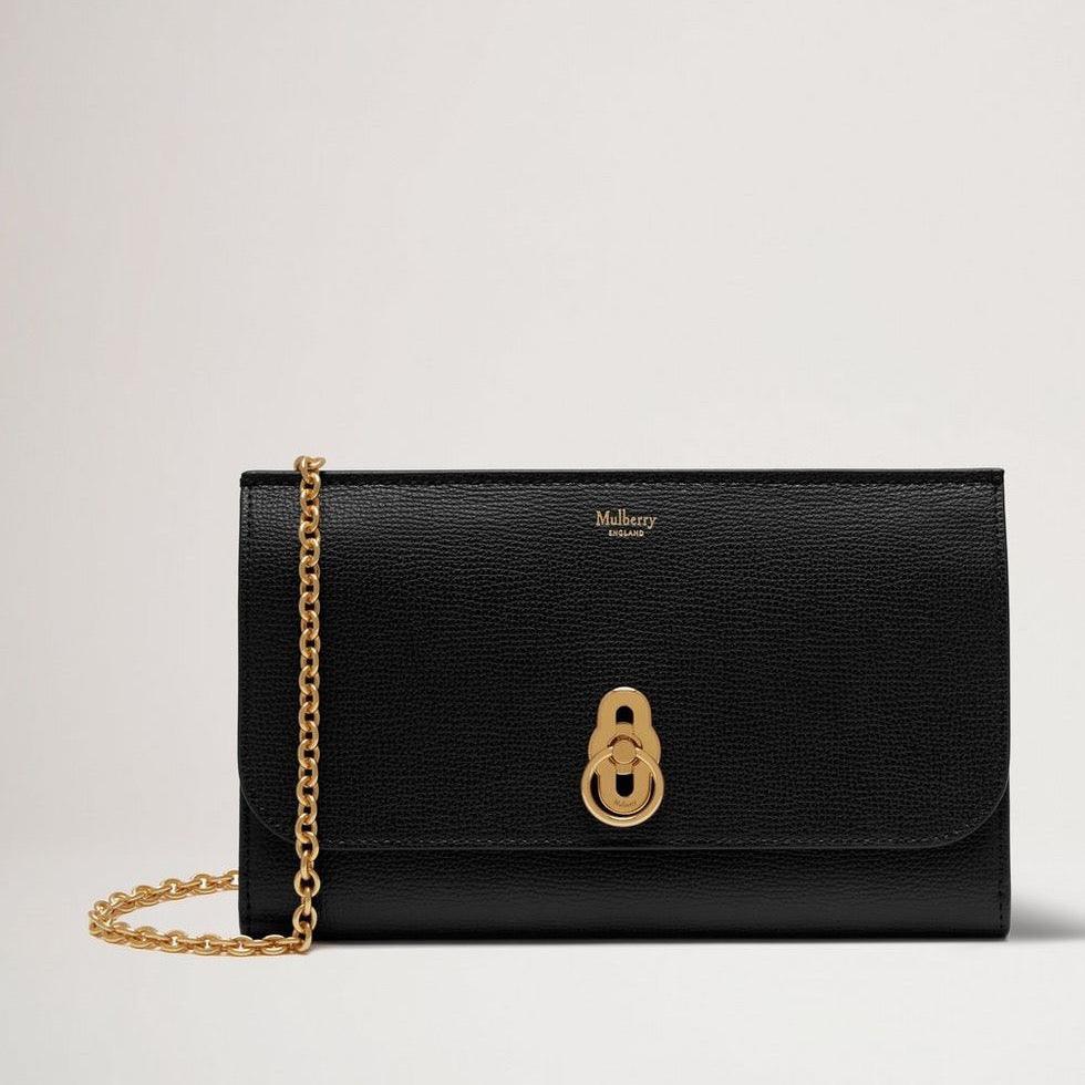 Mulberry De Amberley Clutch Small Classic Grain Black wordt gezien als een elegante zwart leren clutch met gouden ketting en kenmerkende sluiting. ModelRL6090205A100.