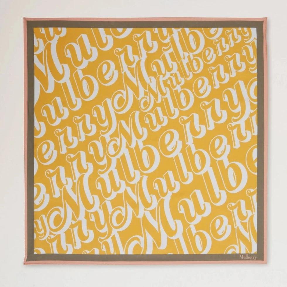 Mulberry Fantasy Logo Square Scarf toont een gele sjaal met wit Mulberry- print en roze rand. ModelVS4802027P504