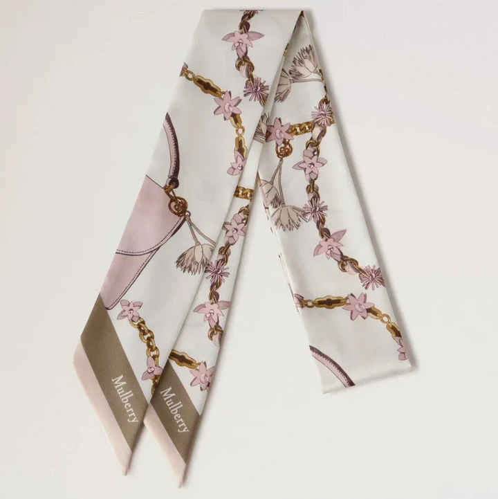 Mulberry Lana Bag and Chains Skinny Scarve Eggshell/Blossom Pink toont een slanke zijden sjaal met roze en gouden kettingdetails. ModelVS4849115W569