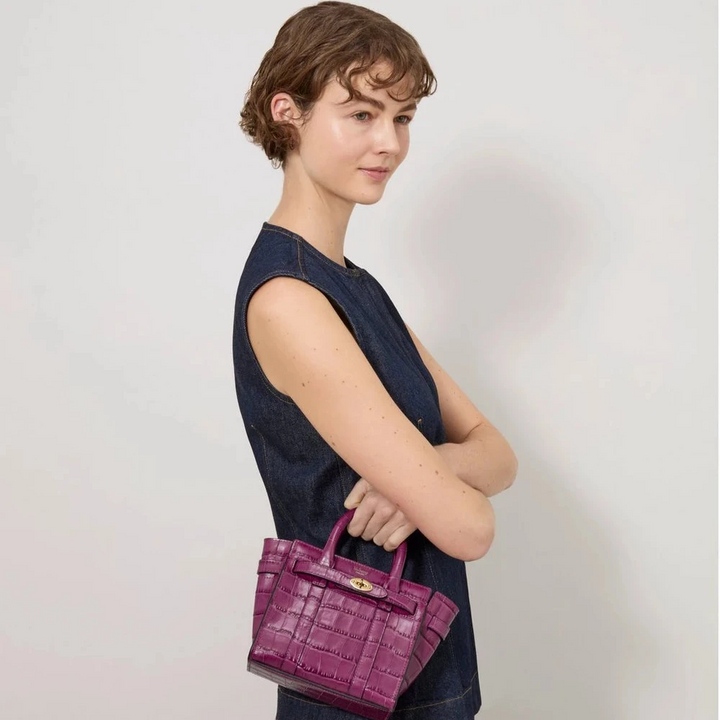 Mulberry Micro-ritssluiting Bayswater Orchid Bloom Shiny Small Croc wordt gedragen in de hand van een vrouw. ModelRL8691641J512