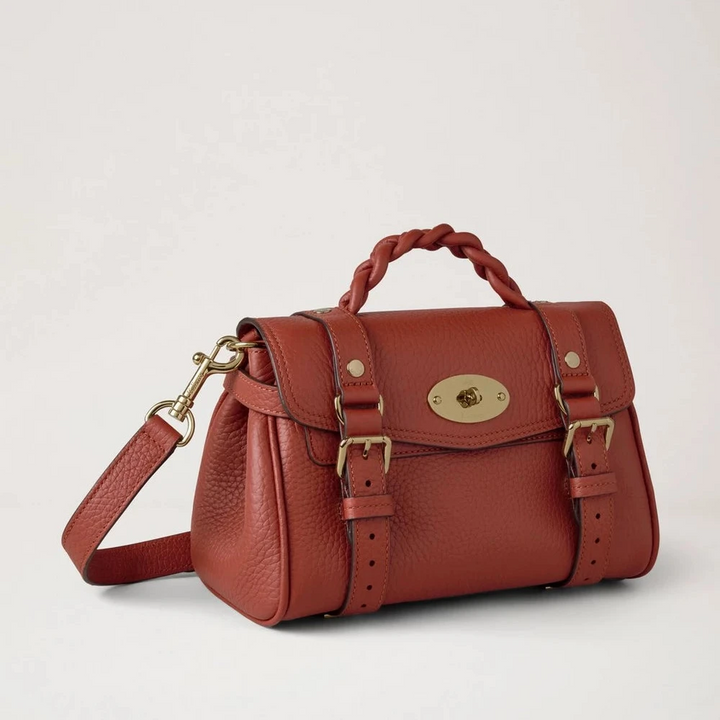 Mulberry Mini Alexa Heavy Grain Rust toont een klein, roestkleurig leren tasje met gevlochten handvat en goudkleurige details. ModelRL6595736L190