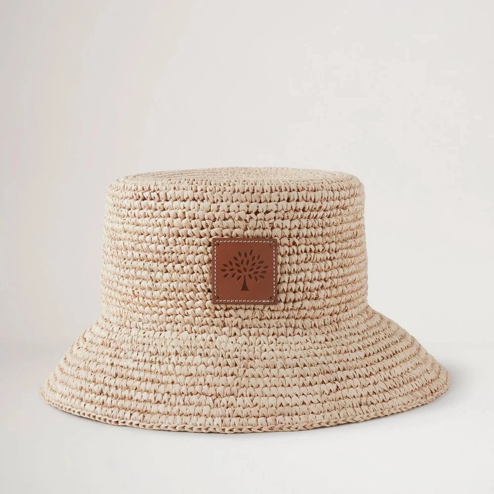 Mulberry Summer Raffia Bucket Hat toont een helder gevlochten raffia zomerhoed met leren detail aan de voorkant. ModelVH4097807H120