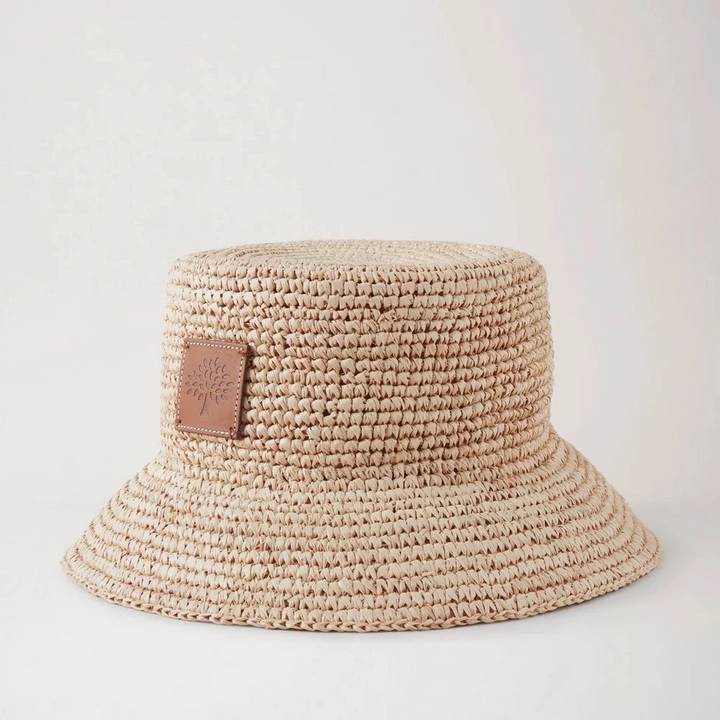 Mulberry Summer Raffia Bucket Hat toont een helder gevlochten raffia zomerhoed met leren patch. ModelVH4097807H120.