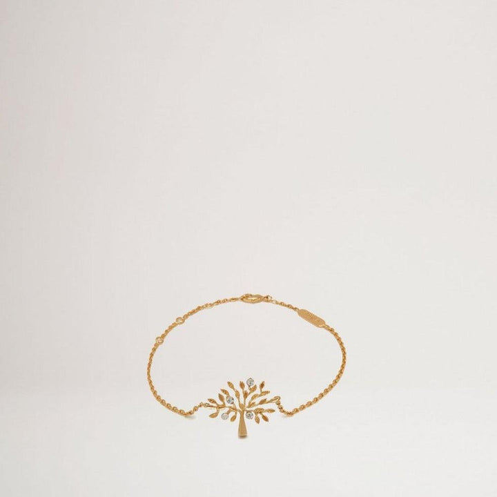 Mulberry Boomarmband Messing Metaal toont een gouden armband met een boomhanger in een eenvoudige, lichte omgeving. ModelQB2266000N637