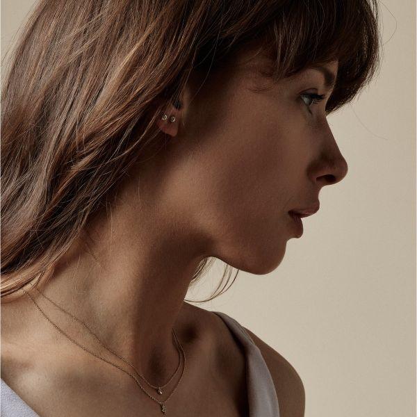 Nuran 14kt Zoe-oorbellen verschijnen discreet op het oor van een vrouw, eenvoudig en elegant in goud. Modelo2314-006rg-2.