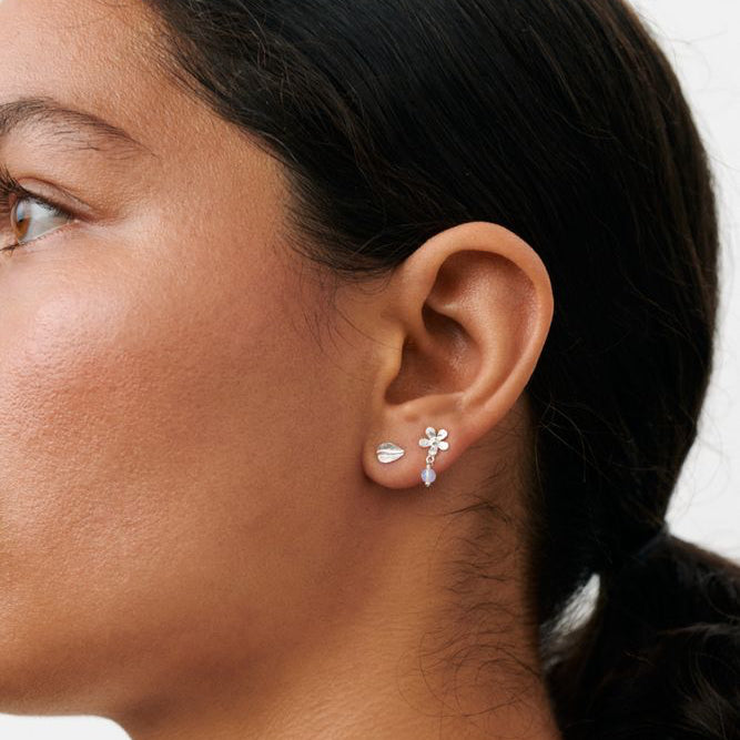 Pernille Corydon Meadow Earring Box in zilver wordt getoond in het oor van het model, glanzende afwerking en bloemdetail. Model C-121-S-1.