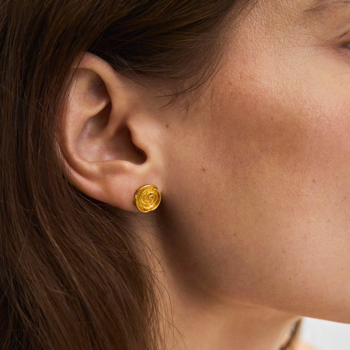 Pernille Corydon Medium Roségoud vergulde oorknopjes dicht bij het oor afgebeeld, elegant goudkleurig detail. Model E-536-GP-1