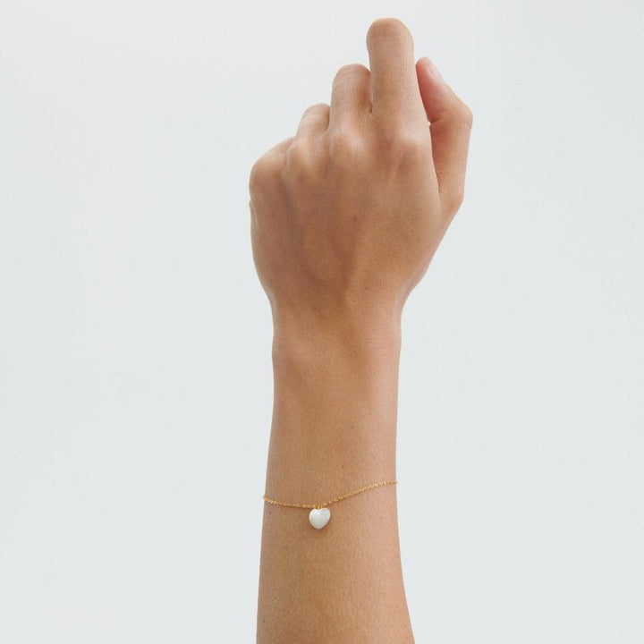 Pernille Corydon Oceaanhart vergulde armband afgebeeld op pols met witte harthanger, model B-387-GP