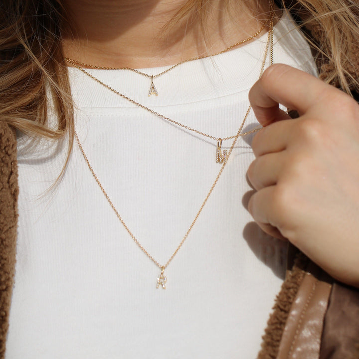 ro copenhagen mijn collectie met diamanten, gouden kettingen met letterhanger gedragen op witte blouse, Model p114y2-001-2