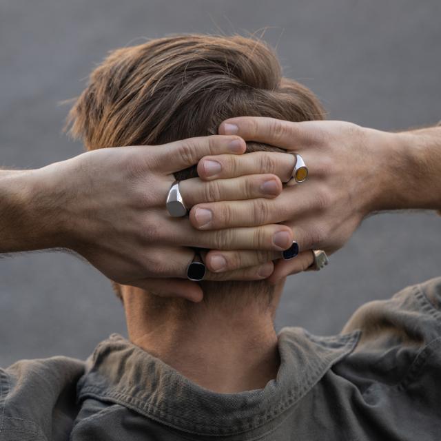 Zoon van Noa herenring in gepolijst zilver gezien aan de hand van een man in natuurlijk buitenlicht. Model 125104-9-001-2