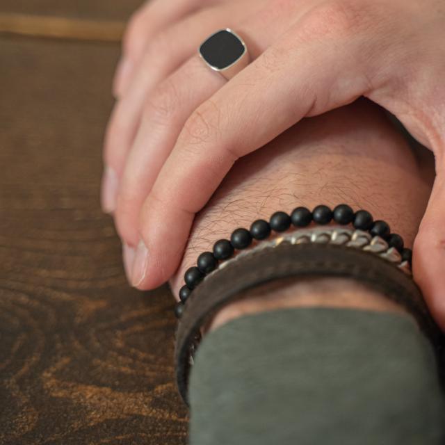 Zoon van Noa herenring in zilver met onyx gedragen bij de hand dicht bij leren armband, model 106700009-001