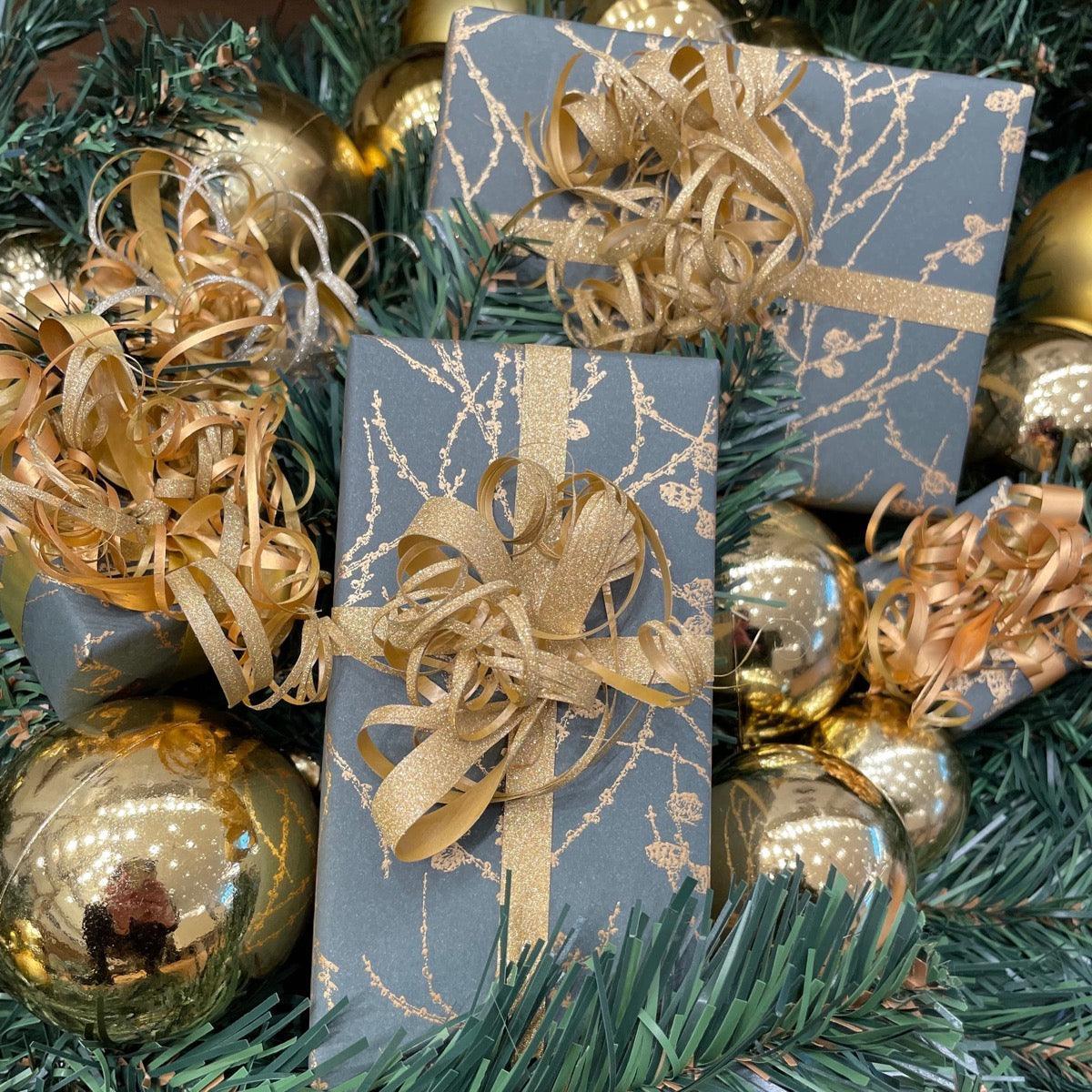 gratis inpakkende kerstcadeaus--1, geschenkdozen van donker papier met gouden linten omgeven door kerstversieringen. Model gratis inpak-kerstcadeautjes--1