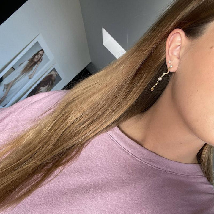 Jeberg Jewellery Ocean Pearl vergulde oorbel afgebeeld op het oor, elegant ontwerp met parel- en gouden details. Model 51720-2