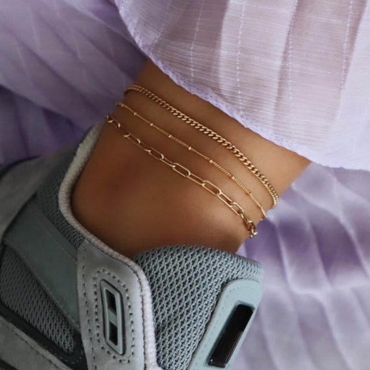 Jeberg Jewellery Saga Paner Enkelbandje in verguld zilver wordt samen met andere kettingen op de enkel weergegeven. Model 4535-G-4535-G-2