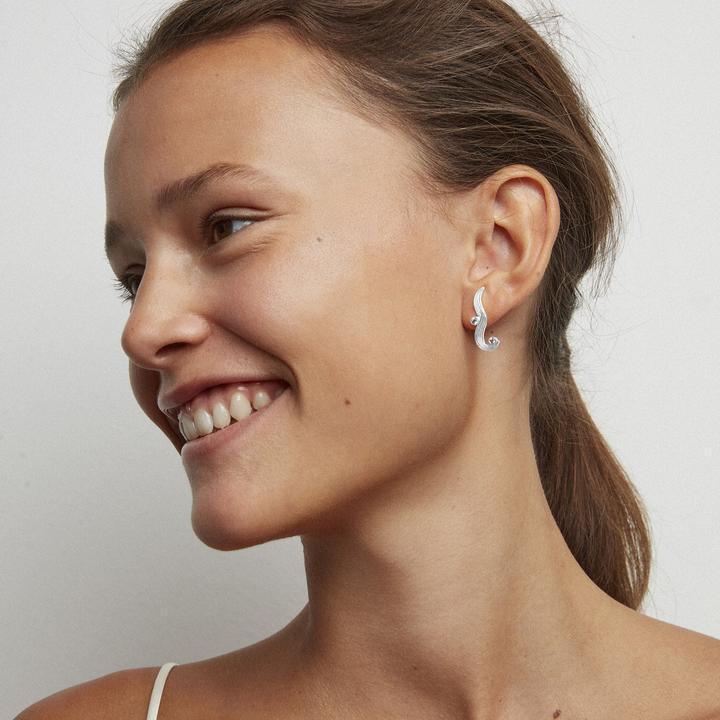 Polar Jewelry The Darning Needle zilveren oorring gedragen door model, vanaf de zijkant getoond. Model st-l-sl-wz-00335-2.