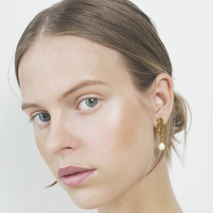 Polar Jewelry The Empress Vergulde oorbellen afgebeeld op model met pareldetail en organische vorm, model TEM-HS-GD-WP-00205-2