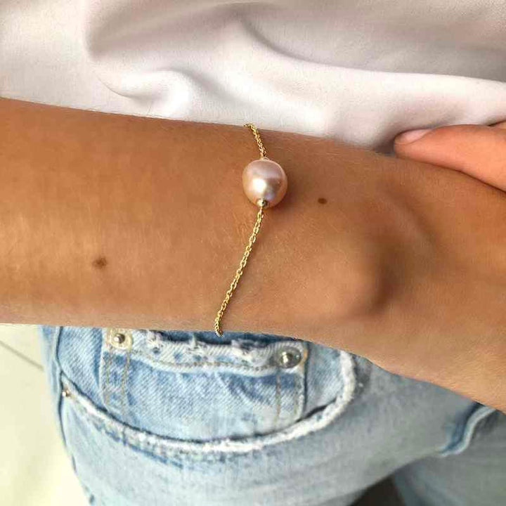 ro copenhagen 18kt joy-armband met roze barok wordt om de pols getoond, elegante gouden armband met parel. Model 192l0013-002