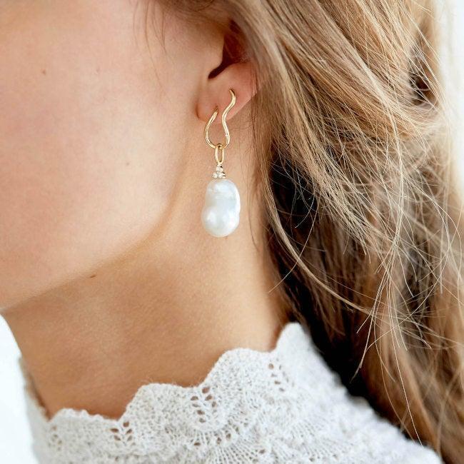 RO Copenhagen 18kt Enjoy barokke parelhanger afgebeeld op het oor, prachtige barokke parel in gouden ophanging. Model 106699-2